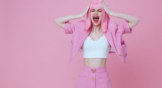 Positive young woman in a pink suit gesturing with his hands emotions fun Studio Model unaltered. High quality photo